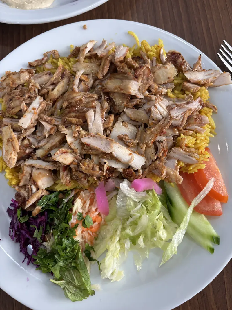 Chicken shawarma piled over golden rice with fresh salad